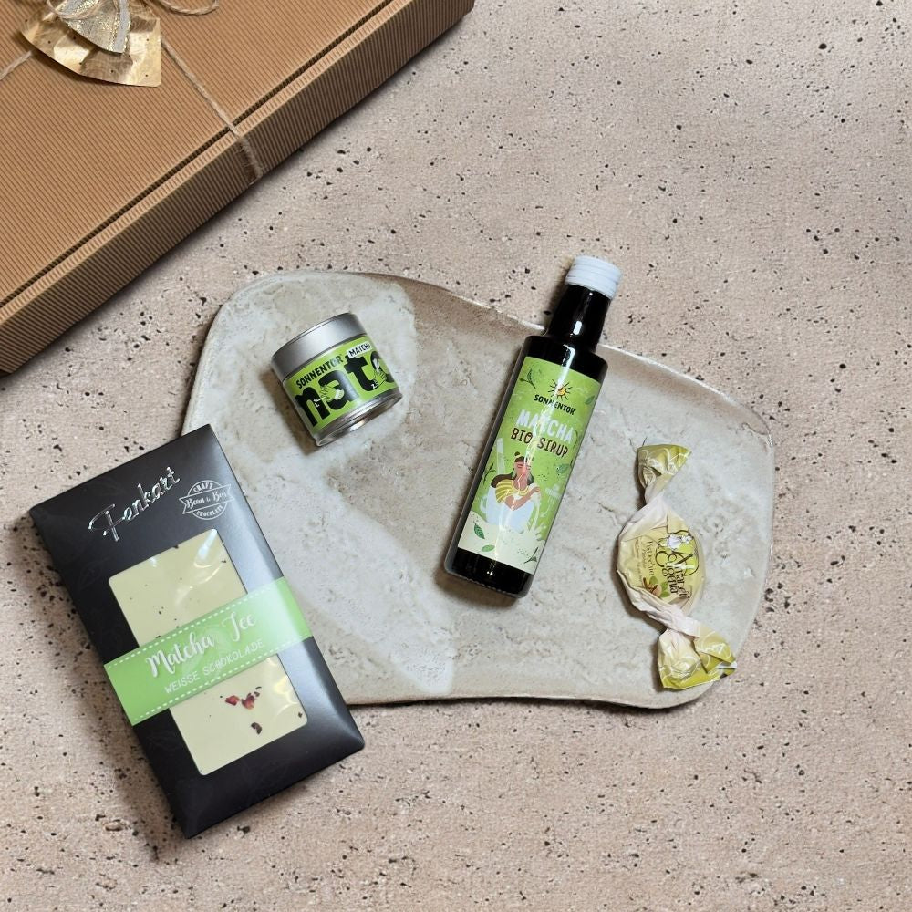 Ausgepackte Matcha Geschenkbox mit Sonnentor Matcha Sirup Matcha Bio Grüntee Fenkart Schokolade Matcha Tee und Brutti e Buoni Amaretti