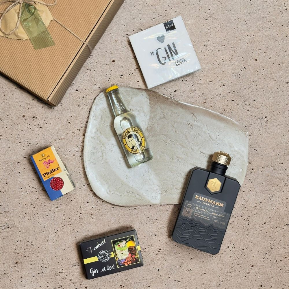 Ausgepacktes Gin Geschenkset mit Kaufmann Spirits Mountain Gin Thomas Henry Tonic Fenkart Gin Schokolade Sonnentor Pfeffer und ppd Servietten