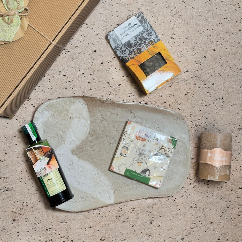 Ausgepackte Steirische Spezialitäten Geschenkbox mit Maitz Kürbiskernöl SteirerKraft Kürbiskerne geröstet Sonnentor Ingwer Ruhe Tee und beiger Stumpenkerze