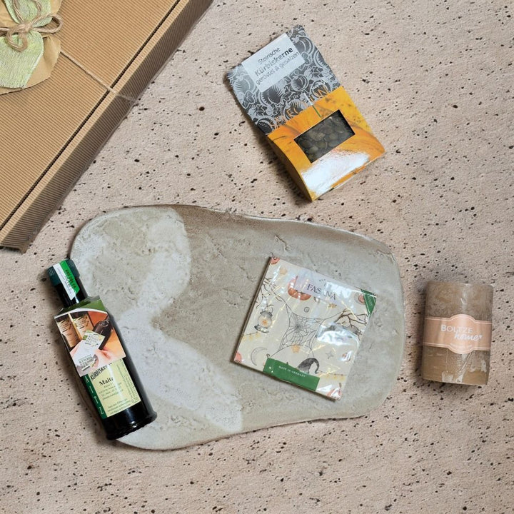 Ausgepackte Steirische Spezialitäten Geschenkbox mit Maitz Kürbiskernöl SteirerKraft Kürbiskerne geröstet Sonnentor Ingwer Ruhe Tee und beiger Stumpenkerze