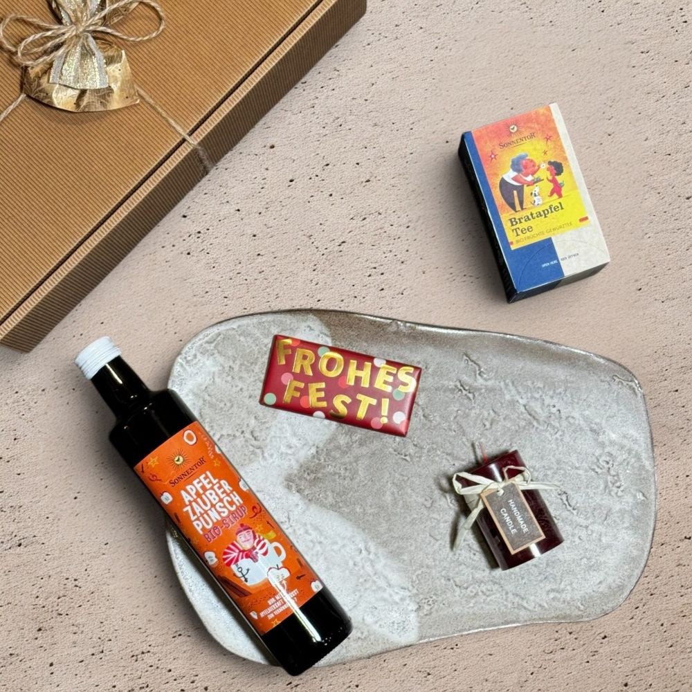 Ausgepacktes Apfel Punsch Geschenkset mit Sonnentor Apfelzauber Punsch Sirup bio Sonnentor Bratapfel Tee Grafik Werkstatt Schokolade Frohes Fest und bordeaux Blending Colors Kerze