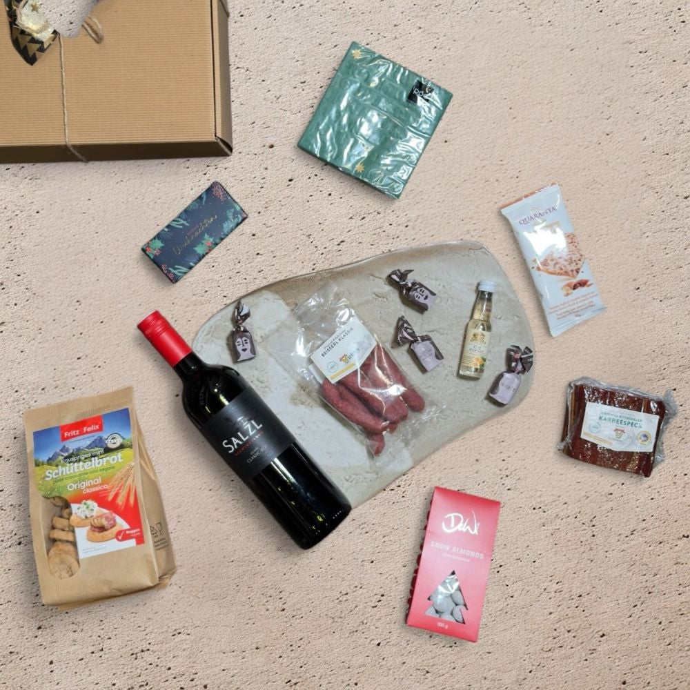 Ausgepackte Wein Geschenkbox Österreich mit Salzl Cuvée Classic Rot 2022 Metzgerei Huber Karreespeck Hubers Beisserl Prinz Alte Marille Fritz Felix Mini Schüttelbrot DeWi Schneemandeln Quaranta Florentine Grafik Werkstatt Schokolade ppd Christmas embossed